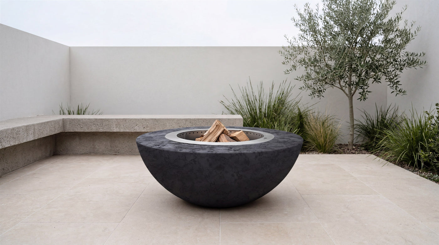 Luna smokeless fire pit in Raven GFRC, unlit in a minimalist courtyard, daylight